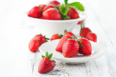 Juicy fresh strawberries in a bowl on a white wooden background, selective focusの写真素材
