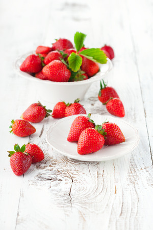 Juicy fresh strawberries in a bowl on a white wooden background, selective focusの写真素材
