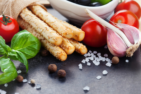 Grissini bread sticks with sesame, sea salt and basil on old black background, selective focusの写真素材