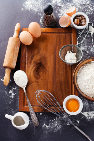 Ingredients and tools for baking - flour, eggs and rolling pin on the black background, top viewの写真素材