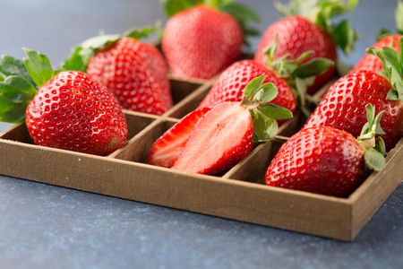 Fresh berries strawberries in wooden box on dark blue background, selective focusの写真素材