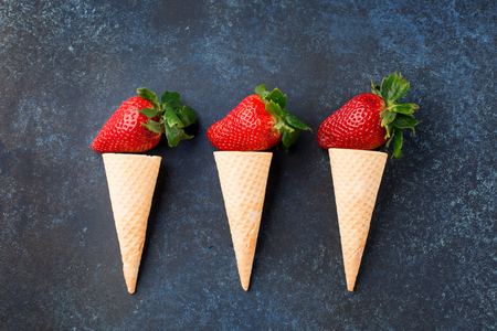 Fresh strawberries in waffle cones, healthy summer food concept, top view, dark blue backgroundの写真素材