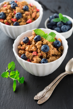 Healthy breakfast with granola, milk, honey and fresh berries on black background, selective focusの写真素材
