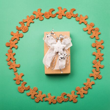 Christmas or new year composition. Gift inside round frame made of winter gingerbread cookies on...