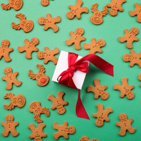 Christmas or new year composition. Gift and winter gingerbread cookies on green background. Holiday...
