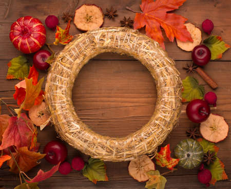 Autumn floral frame, web banner. Wreath of dry maple, oak leaves, flowers and apple. Wooden table background. Fall, Halloween or Thanksgiving Holiday design. Flat lay, top view.の写真素材