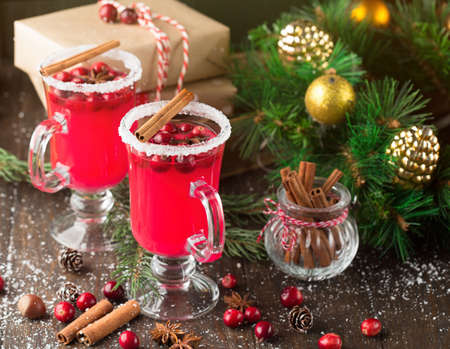 Festive Cranberry drink on Christmas background with fir branches and fresh berries, selective focus. Holiday concept. Dark rustic wooden table, Winter timeの写真素材