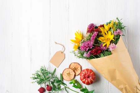 Autumn bouquet of yellow and pink flowers on white wooden background. Autumn concept for Thanksgiving day or for other holidays. Flat lay, copy space.の写真素材
