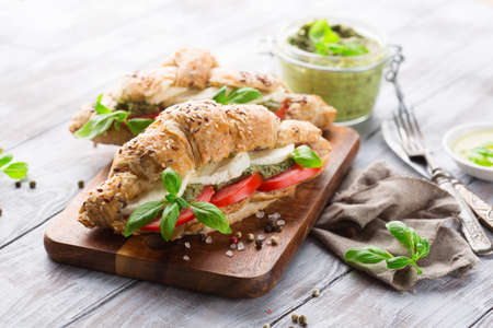 Ð¡runchy wholegrain croissants with mozzarella, tomato and homemade pesto sauce on rustic white wooden background, selective focusの写真素材