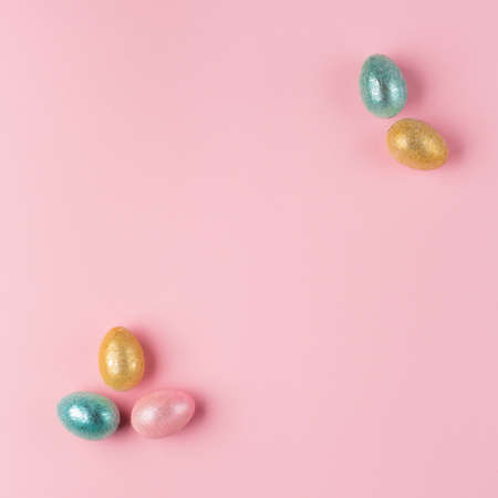 Gold, silver shiny Easter eggs on pink pastel background with space for text. Flat lay image...