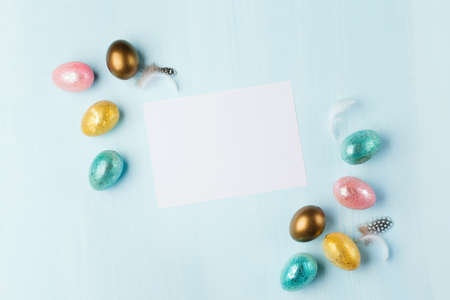 Gold, silver shiny Easter eggs on blue pastel background with space for text. Flat lay image...