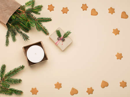 Christmas or New Year composition. Christmas zero waste eco-friendly concept. Festive Xmas gift, gingerbread cookies, fir branches, soy candle on natural beige background. Copy space, tpo view.の写真素材