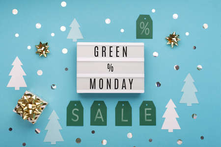 Green Monday sale text on white Lightbox with gold gift box and Christmas decorations on blue paper background. Design for promotion of winter end of year sale. Top view, copy space.の写真素材