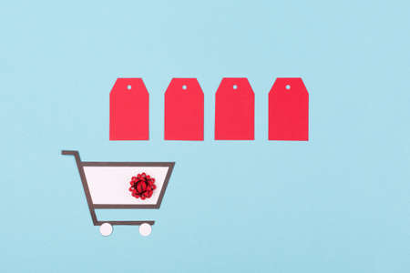 Super Sale day or Singles day concept. Shopping trolley, gift boxes and red tags on blue paper...