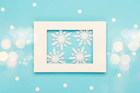 Christmas or winter composition. Frame, snowflakes and festive decorations on pastel blue...