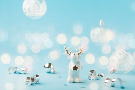 Christmas card with small glass white reindeer, silver decorations, mirror disco balls on light blue background. Winter festive concept, copy space.の写真素材