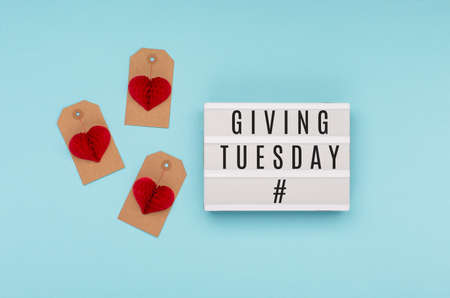 Giving Tuesday, global day of charitable giving after Black Friday shopping day. Charity, give help, donations support concept with text message on lightbox, red paper heart on blue background.の写真素材