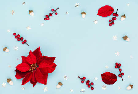 Christmas holiday winter New Year festive card. Xmas red flower poinsettia, silver snowflakes, acorns on blue paper background. Flat lay, top view, copy space.の写真素材