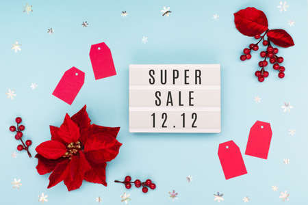 12.12 Super Sale text on white lightbox, Christmas flower poinsettia, red paper tags and snowflakes...