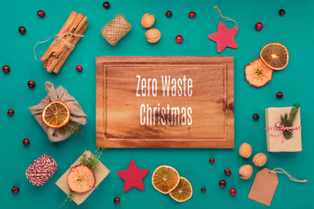 Zero waste Christmas and New Year winter concept. Trendy eco friendly handmade gifts, gingerbread cookies, cinnamons, fir branches and cranberries on tidewater green background. Copy space, flat layの写真素材
