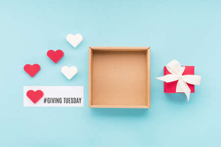 Giving Tuesday, global day of charitable giving after Black Friday shopping day. Charity, give help, donations support concept. Text message, gift box, red hearts on blue background.の写真素材