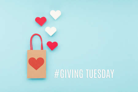 Giving Tuesday, global day of charitable giving after Black Friday shopping day. Charity, give help, donations support concept with text message, red hearts and shopping bag on blue background.の写真素材