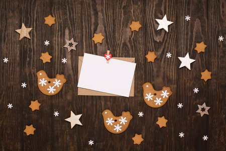 Holiday Christmas gingerbread cookies with empty card, festive gift box, snowflakes and decorations on dark wooden background. Top view, copy space, flat lay. Winter time concept.の写真素材