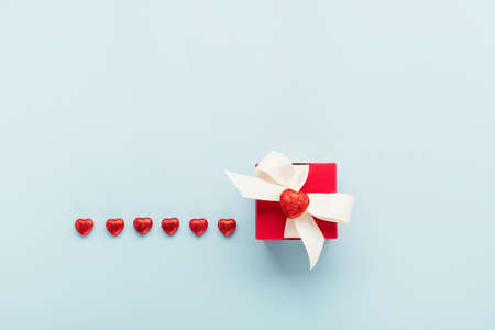Valentine's Day holiday card. Red gift box and hearts on pastel blue background. Valentines day...