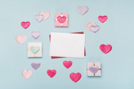 Pink textile hearts, empty card and gifts on blue background. Valentines day concept. Flat lay, top view, copy space. Festive holiday greeting card for Valentines, Birthday, Woman or Mothers Day.の写真素材