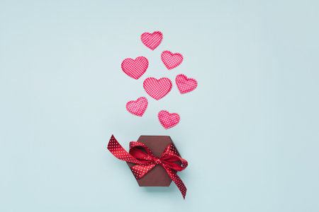 Pink textile hearts with polka dots and gift box on blue background. Valentines day concept. Flat lay, top view, copy space. Festive holiday greeting card for Valentines, Birthday, Woman, Mothers Day.の写真素材