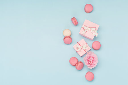 Valentines Day card. Pink gifts with ribbon and macaron macaroon cookie on blue background. 8 March, Womens Mothers Valentines Day, Birthday. Flat lay, top view, copy space.の写真素材