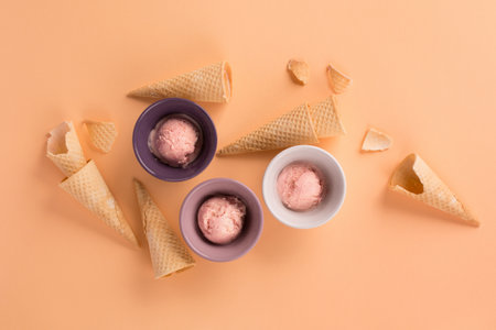 Homemade yogurt strawberry ice cream, sweet waffle cones on pastel pink background. Healthy low...