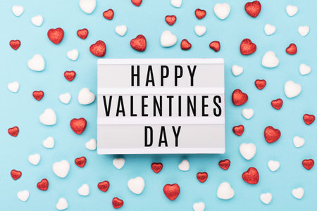 Elegant festive composition for Valentine's day. Red white glitter hearts and lightbox on blue paper background. Happy Valentines Day concept. Flat lay, top view, copy space.の写真素材