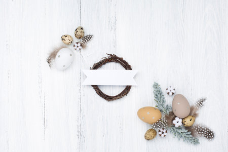 Craft Easter composition with Easter quail eggs, nest and cotton flowers on white wooden background. Top view, copy space, flat lay. Easter festive greeting card.の写真素材