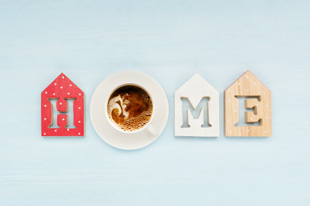 Word home on blue wooden background and cup of coffee with milk. Top view, copy space. Home word concept.の写真素材