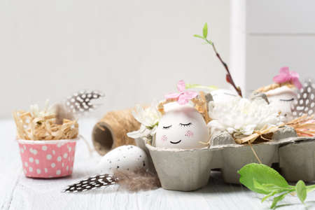 Zero waste Easter concept with white cute eggs, tree branches, quail feathers and spring flowers on white wooden background, copy space. Easter festive holiday greeting card.の写真素材