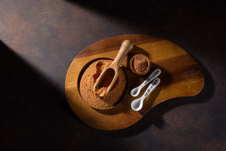 Bowl with organic carob powder on dark rustic wooden background. Selective focus, copy space. Super...
