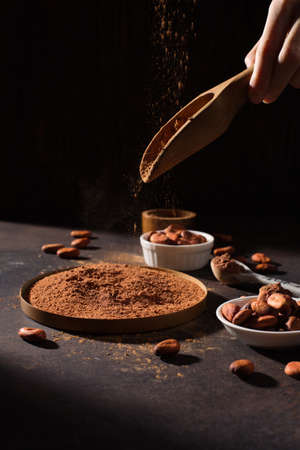 Bowls with organic cocoa powder and aromatic raw cocoa beans on dark rustic wooden background. Selective focus, copy space. Super brain food concept.の写真素材