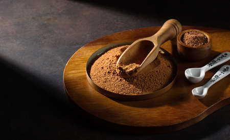 Bowl with organic carob powder on dark rustic wooden background. Selective focus, copy space. Super brain food concept.の写真素材