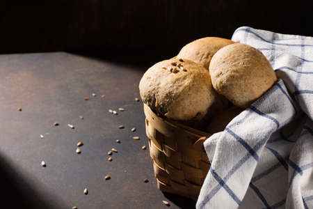 Homemade wholemeal rye wheat buns with seeds on wooden table, dark rustic background. Selective focus, copy space. Alternative handmade food cooking concept.の写真素材