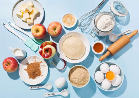 Cooking baking background with ingredients, fresh apples, spices and utensils on blue table. Baking traditional apple pie concept. Top view, copy space,, hard shadows.の写真素材