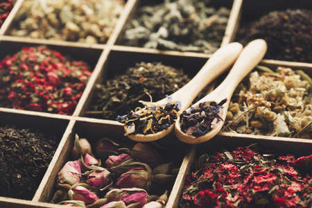 Different kind of Dry tea - green, black, mint, rose and chamomile, wooden spoons in box. Tea time...