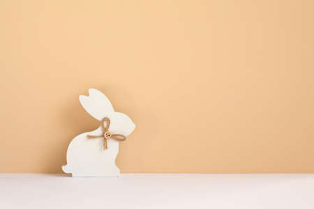 Minimal Easter card with white wooden bunny on natural beige background. Zero waste easter concept. Eco friendly lifestyle, copy space.の写真素材