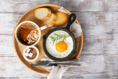 Pan of fried egg, crispy baguette, fruit jam and cup of coffeeの写真素材