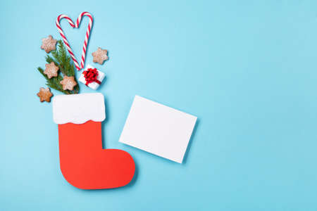 St. Nicholas Day - Red boot with sweets, spicy ginger cookies and gifts for December 6th on blue background. German, Netherlands, Belgium Christmas consumption called Nikolaus, top view, copy space.の写真素材