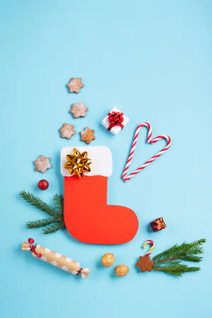 St. Nicholas Day - Red boot with sweets, spicy ginger cookies and gifts for December 6th on blue background. German, Netherlands, Belgium Christmas consumption called Nikolaus, top view, copy space.の写真素材