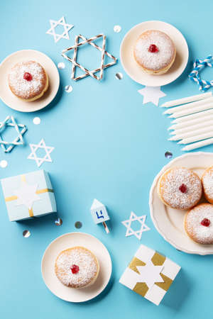 Hanukkah sweet donuts sufganiyot (traditional donuts) with fruit jelly jam, gift boxes, spinnig...