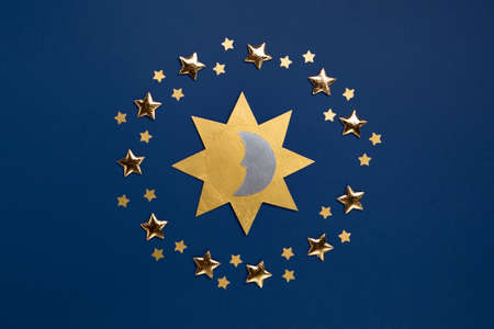 Winter solstice day holiday, December 21. Longest night in the year concept. Sun, moon and golden stars symbol on dark blue paper background. Flat lay, top view, copy space.の写真素材