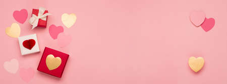 Pink paper hearts and festive gift boxes on pink background. Valentines day banner concept. Flat...