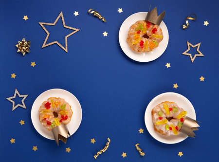 Traditional kings day bread Epiphany cakes on blue background with winter decorations. Roscon de reyes, spanish three kings Christmas sweet cake. Spanish typical dessert of Epiphany day, top view.の写真素材